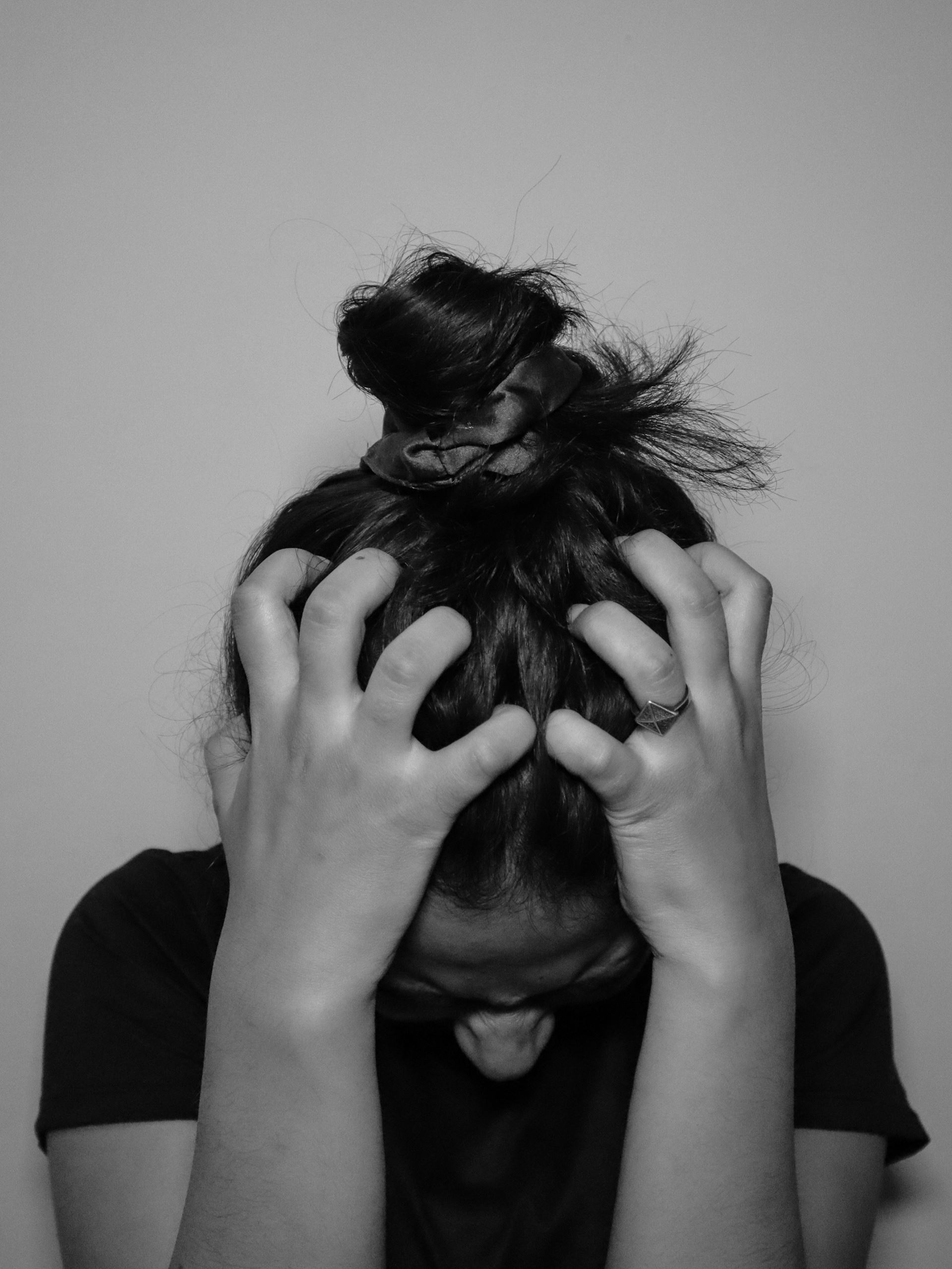 stress woman holding head in hands black and white